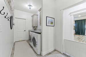 Laundry area with cabinet space, washing machine and dryer, and light tile patterned floors