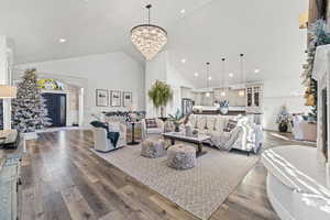 Living area with a fireplace, hardwood / wood-style floors, high vaulted ceiling, a chandelier, and recessed lighting