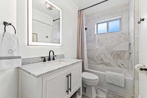 Full bathroom featuring shower / bath combo, vanity, and marble look tiles