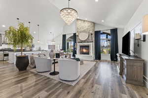 Living area featuring light wood-type flooring, a fireplace, a chandelier, recessed lighting, and high vaulted ceiling