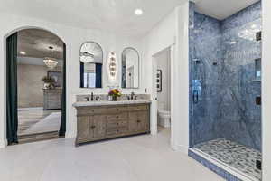 Full bathroom with double vanity, a chandelier, a stall shower, light tile patterned floors, and recessed lighting