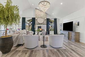 Living area featuring light wood-type flooring, a fireplace, high vaulted ceiling, a chandelier, and recessed lighting
