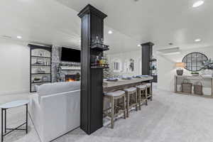 Kitchen with a stone fireplace, light carpet, a kitchen breakfast bar, and recessed lighting