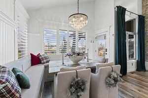 Living area with plenty of natural light, wood-type flooring, a chandelier, and high vaulted ceiling
