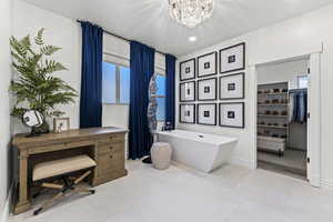 Bathroom with a freestanding tub, a walk in closet, a chandelier, light tile patterned flooring, and recessed lighting