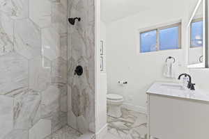 Full bathroom featuring a marble finish shower, vanity, and light marble finish flooring