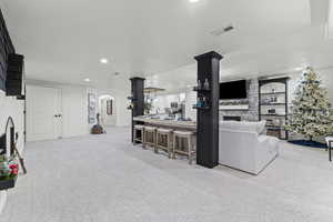 Living area featuring a stone fireplace, arched walkways, light carpet, and recessed lighting