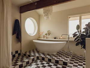 Bathroom with a freestanding bath, a chandelier, and beam ceiling