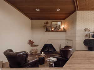 Living area featuring wooden ceiling, brick wall, and wood finished floors
