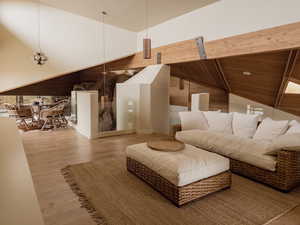 Living room with wood finished floors, wooden walls, and high vaulted ceiling