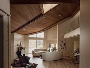 Living area with wood finished floors, high vaulted ceiling, and brick wall