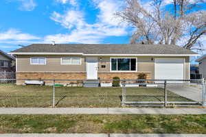 Ranch-style house with an attached garage, brick siding, a shingled roof, concrete driveway, and a fully-fenced front yard