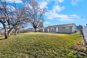 Rear view of property featuring a patio, fully-fenced yard, and mature trees