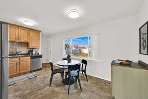 Eat-in kitchen featuring stainless steel appliances, tasteful backsplash, tile flooring, and light brown cabinetry