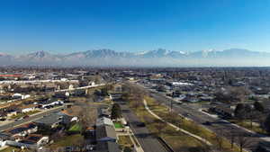 Aerial overview of property's location on a quiet street featuring a mountainous background, and green space with trail across the street.