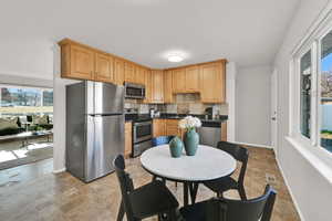 Eat-in kitchen featuring stainless steel appliances, tasteful backsplash, tile flooring, and light brown cabinetry