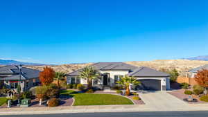 View of front of property with a mountain view, an attached garage, driveway, and stucco siding
