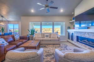 Carpeted living room featuring ceiling fan, healthy amount of natural light, a stone fireplace, and recessed lighting