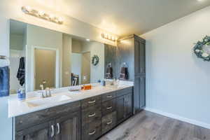 Full bath featuring double vanity and light wood-style flooring