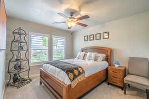 Carpeted bedroom featuring ceiling fan and baseboards