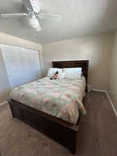 Bedroom with carpet flooring, a closet, a ceiling fan, and a textured ceiling