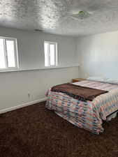 Bedroom featuring dark colored carpet and a textured ceiling