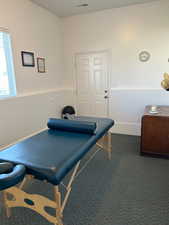 Miscellaneous room featuring dark colored carpet and baseboards