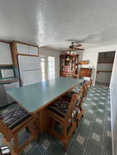 Kitchen with brown cabinetry, french doors, a textured ceiling, stainless steel dishwasher, and freestanding refrigerator