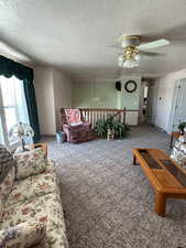 Carpeted living room featuring a textured ceiling and ceiling fan