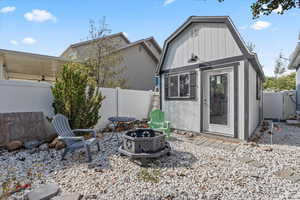 Rear view of property with a fire pit, a fenced backyard, a gambrel roof, and an outbuilding