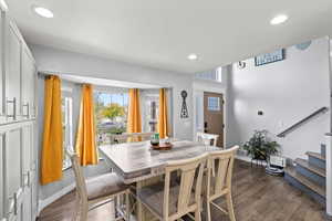 Dining area with dark wood-type flooring, recessed lighting, and stairway