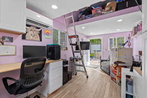 Office with a wall mounted AC, built in desk, light wood finished floors, and recessed lighting