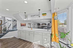 Kitchen with arched walkways, dark wood-style floors, light stone counters, decorative light fixtures, and recessed lighting