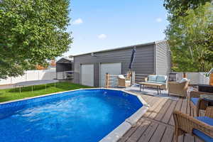 View of pool with a trampoline, an outdoor hangout area, a deck, and an outdoor structure