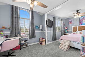 Carpeted bedroom with a ceiling fan, vaulted ceiling, and a desk