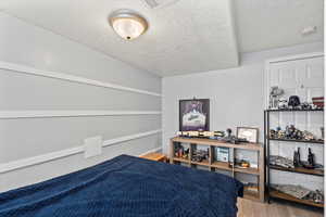 Bedroom with a textured ceiling and wood finished floors