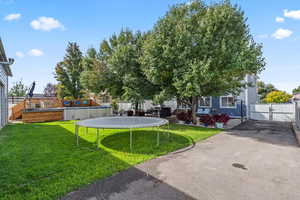 Fenced backyard featuring a gate, a trampoline, and a patio