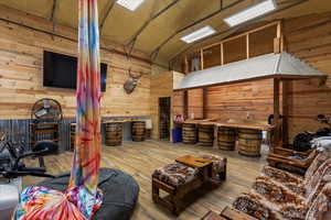 Living area featuring wood walls, high vaulted ceiling, and hardwood / wood-style floors