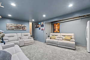 Carpeted living room with recessed lighting and a textured ceiling