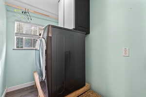 Washroom featuring washer / dryer, cabinet space, and dark wood-style flooring