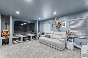 Living room with carpet flooring, a textured ceiling, and recessed lighting