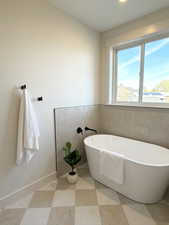 Full bath with a freestanding bath and baseboards
