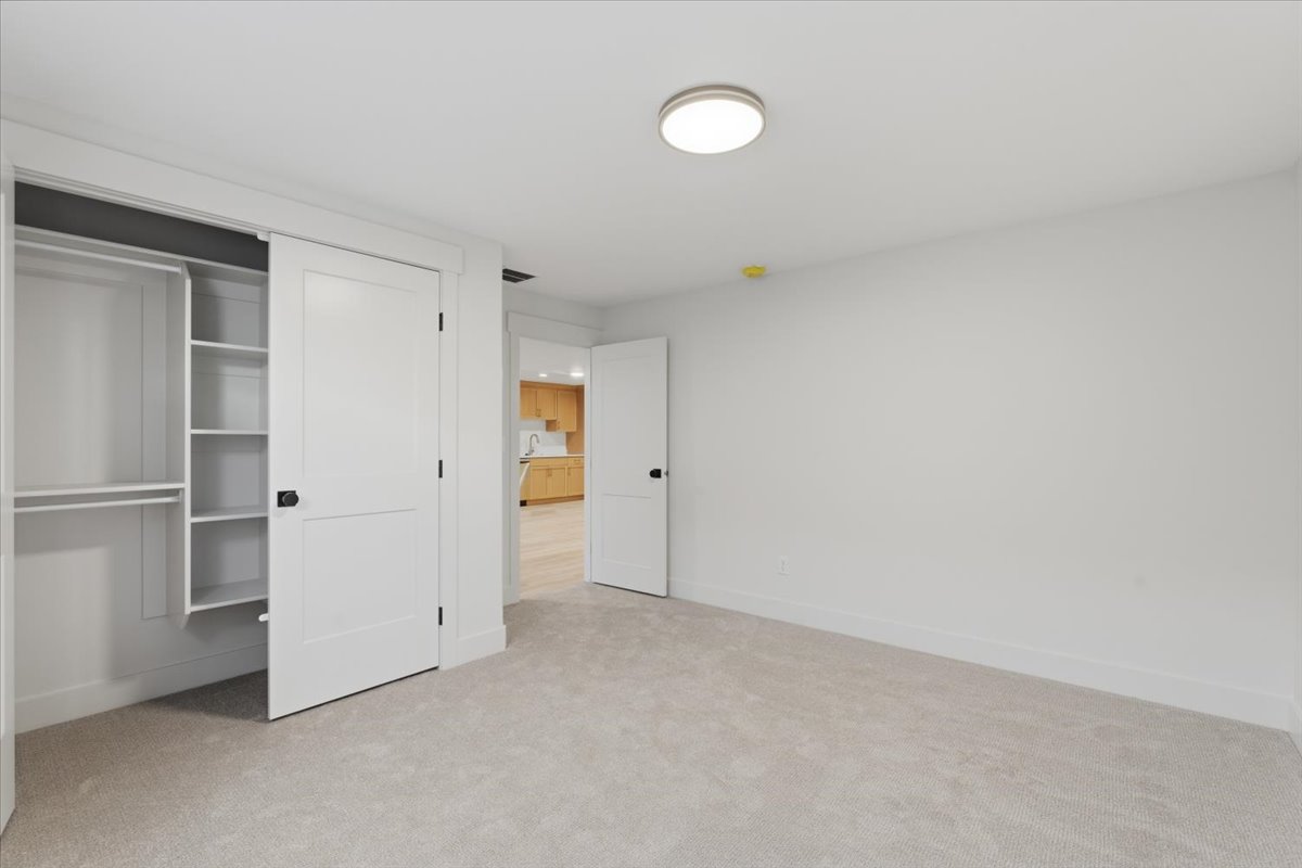 Unfurnished bedroom featuring light carpet and a closet