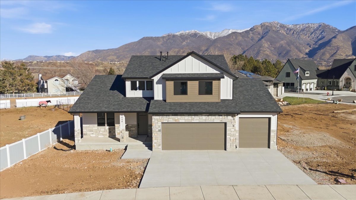 View of front of house featuring board and batten siding, covered porch, stone siding, and a mountain view