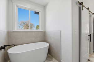 Full bathroom with a soaking tub and tile walls