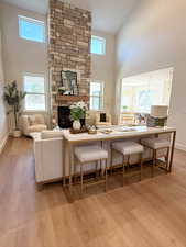Living room featuring a high ceiling, a fireplace, light wood finished floors, and plenty of natural light