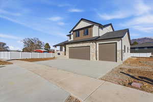 View of front facade featuring board and batten siding, concrete driveway, stone siding, and a garage