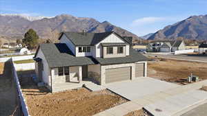 Modern inspired farmhouse with covered porch, a mountain view, driveway, stone siding, and roof with shingles