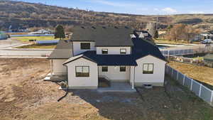 Back of house featuring roof with shingles, a patio area, and a mountain view