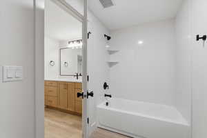 Bathroom featuring vanity, bathtub / shower combination, and light wood-type flooring